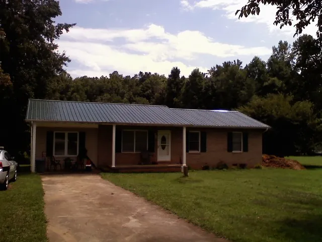 Dark green metal roof on a brick ranch with a covered porch in Ottumwa