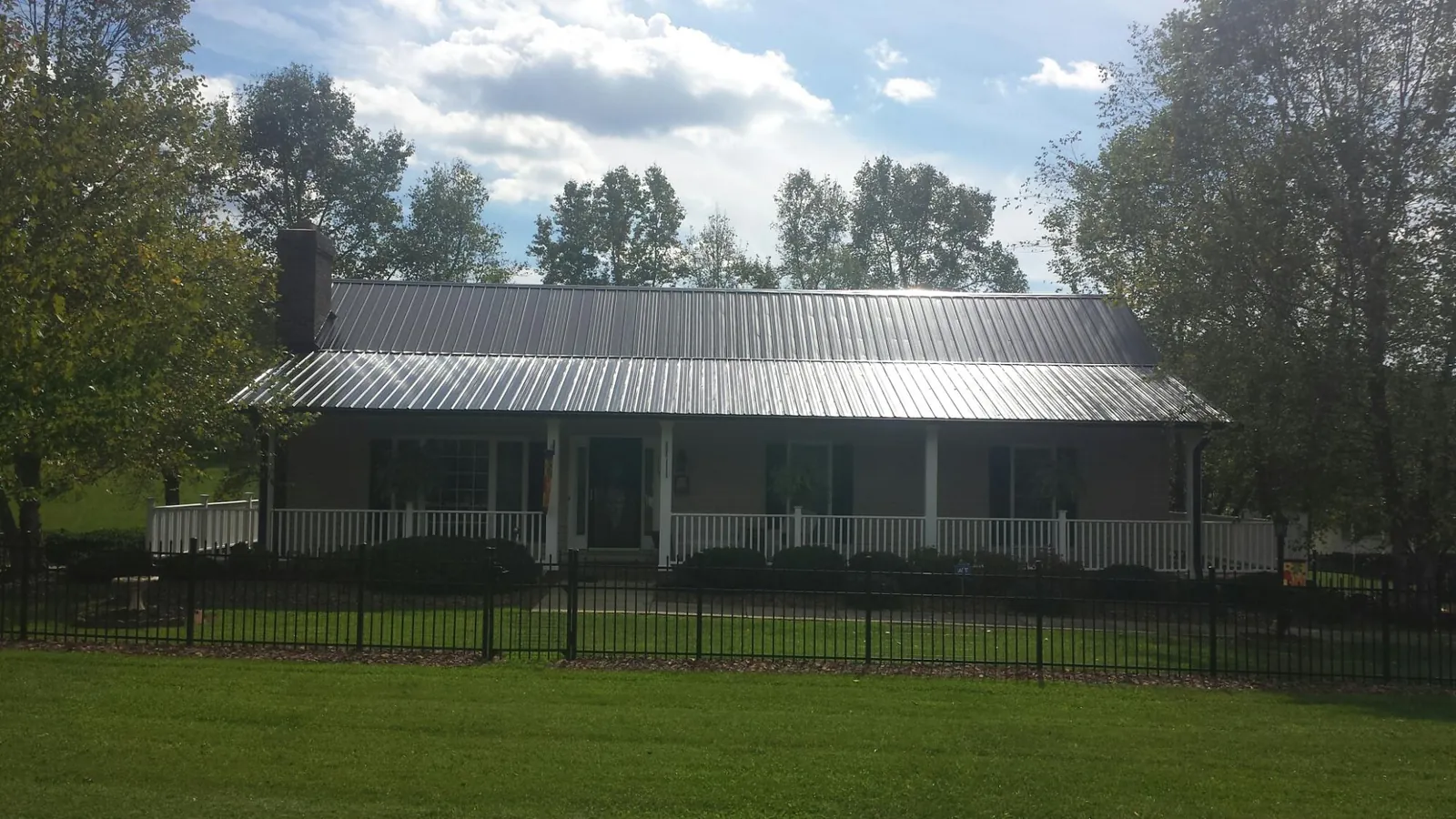 Gray metal roof on a brick ranch with a full width front porch — Gutter Guard Installation work by our crew in Ottumwa