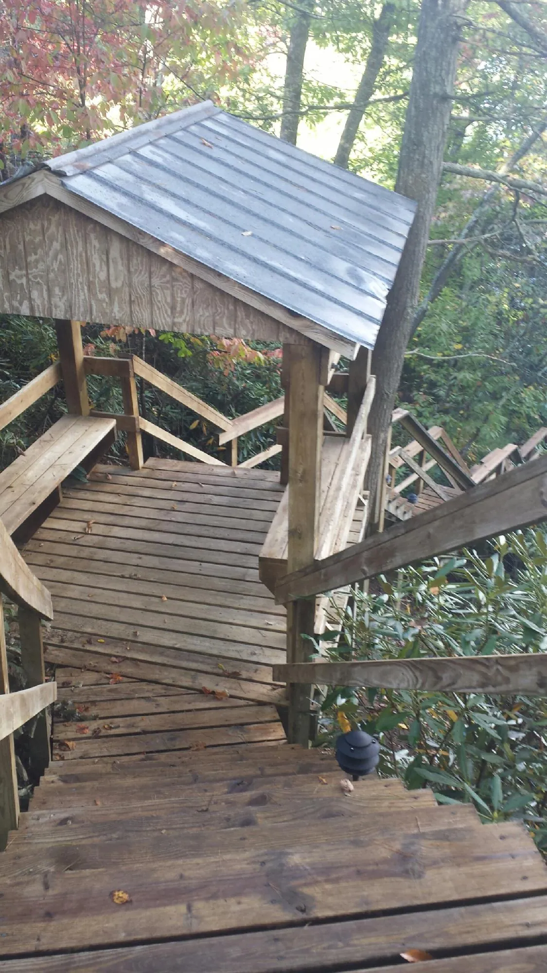 Metal roofed shelter over wooden steps on a wooded walkway — Skylight Repair & Installation work by our crew in Ottumwa