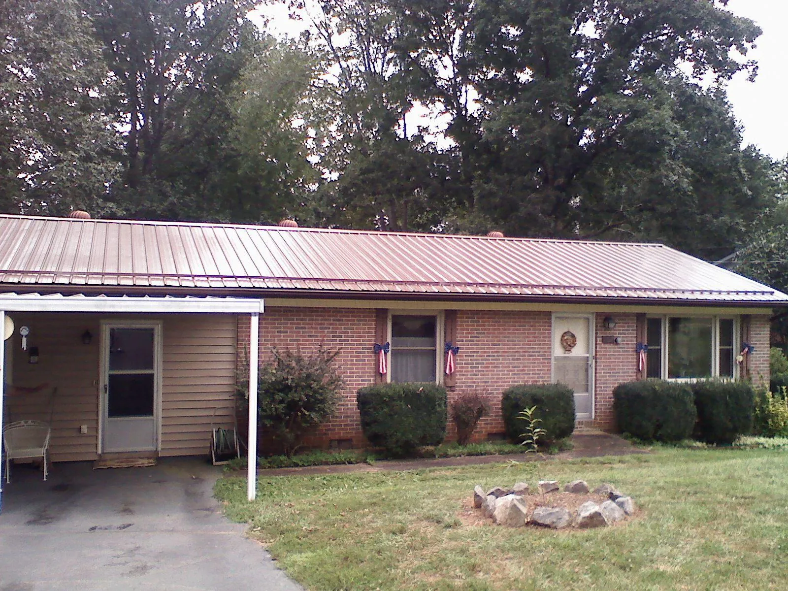 Bronze metal roof and carport on a brick ranch home — Roof Repair work by our crew in Ottumwa