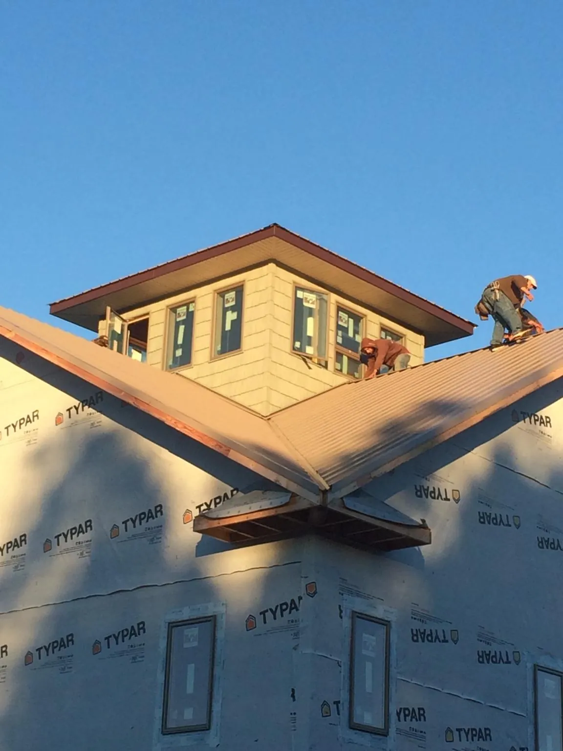 Roofers working around a rooftop cupola on a new metal roof at sunset — Roof Waterproofing in Ottumwa by Roofing Brothers